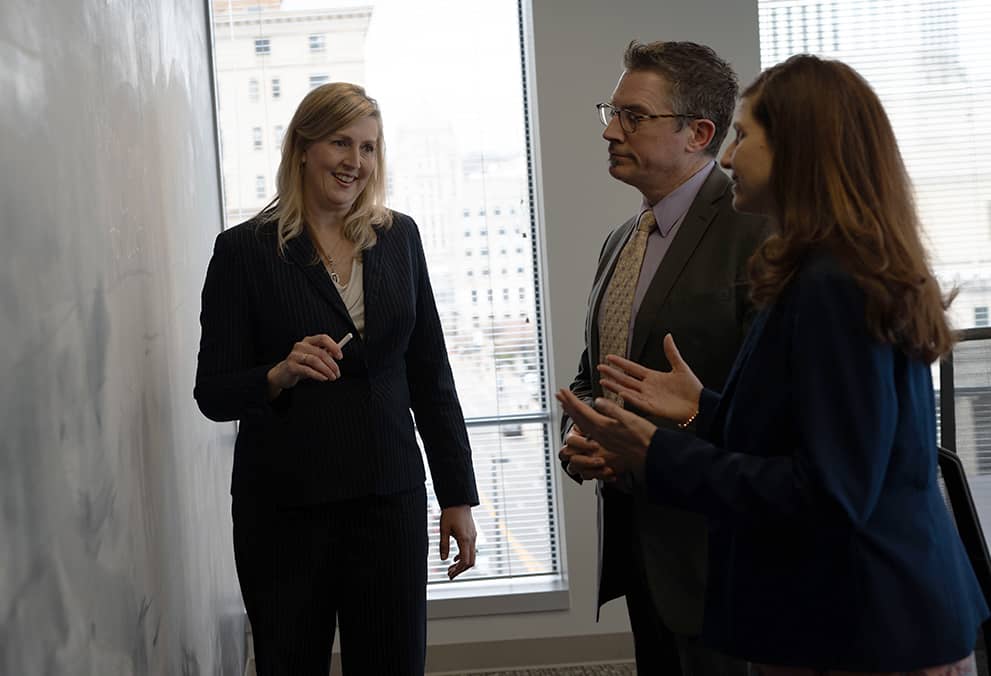Three associates collaborating together next to chalkboard