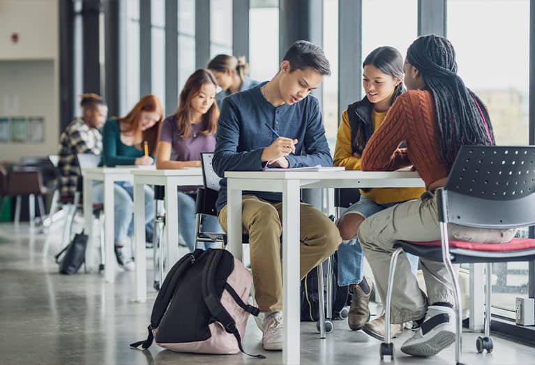 Group of college students studying together around a desk