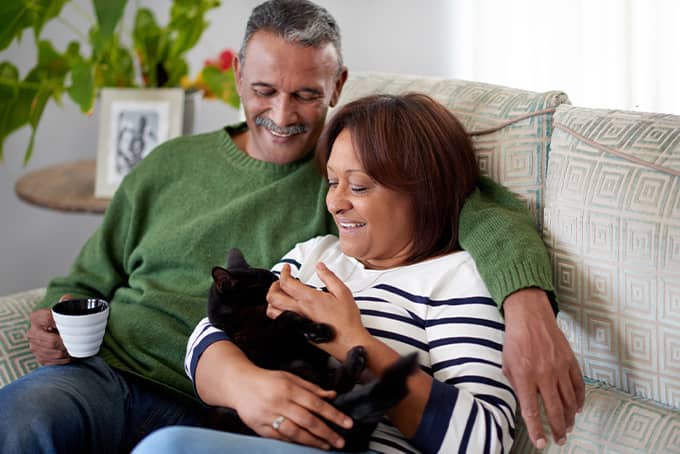 Married couple sitting on the couch with their cat