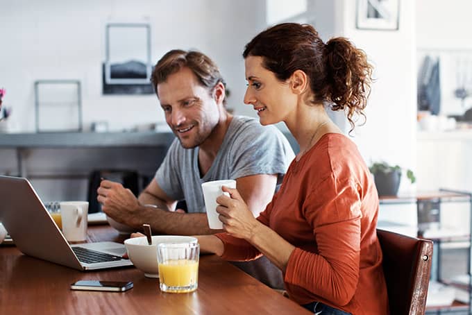 Couple sitting at a table researching annuities on their laptop