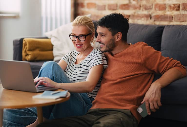 Couple researching online term life insurance on laptop