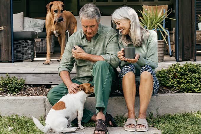 Husband and wife sitting outside with their two dogs enjoying their financial freedom
