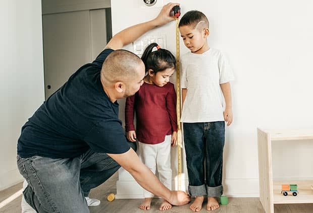 Father measuring childrens height