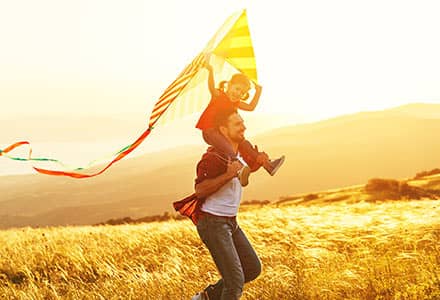 Father holding son on shoulders with a kite