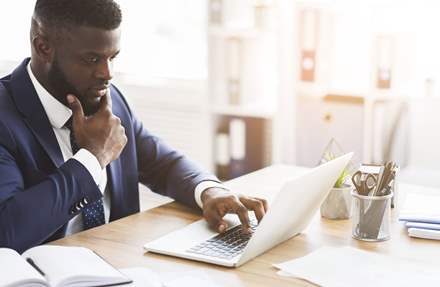 Businessman studying his laptop screen with concern.