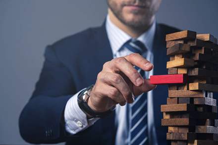 Businessman isolating a red, infected piece from a Jenga tower.