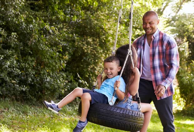 father enjoy playing with children on tire swing