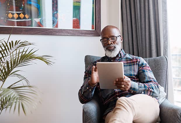 man sitting in a chair using an ipad