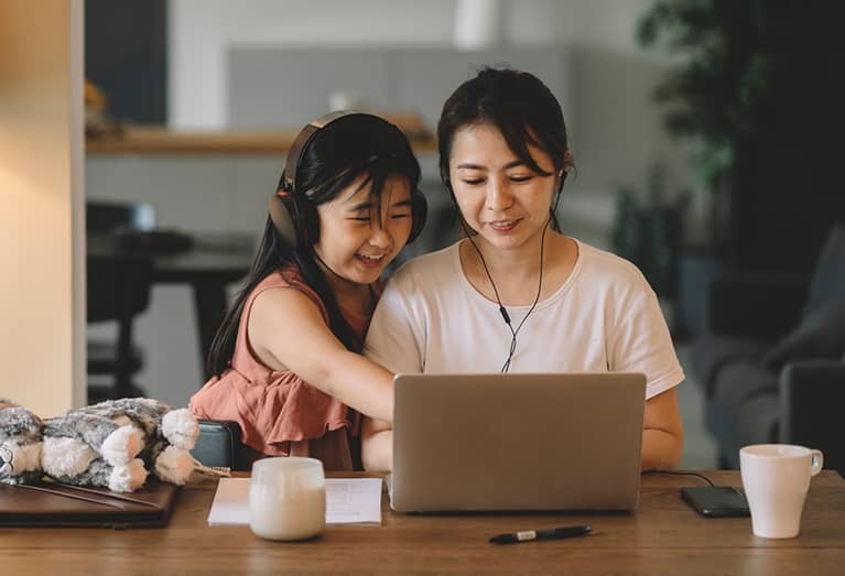 Mother researching life insurance while daughter watches next to her