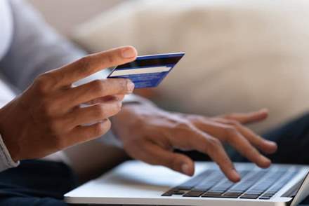Person using their credit card information to make an online purchase via laptop.