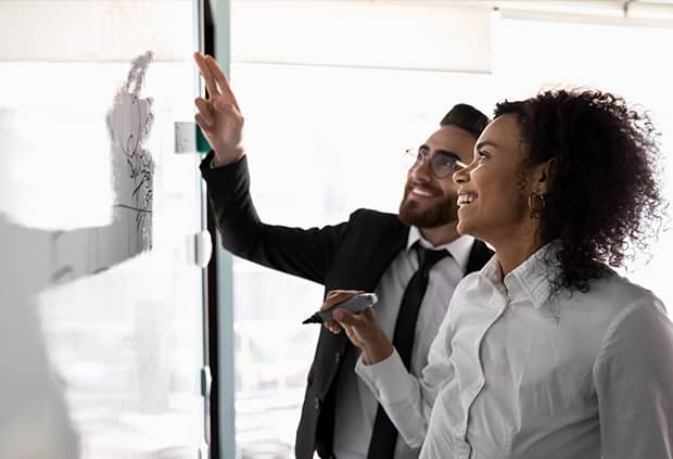 Two coworkers working on white board