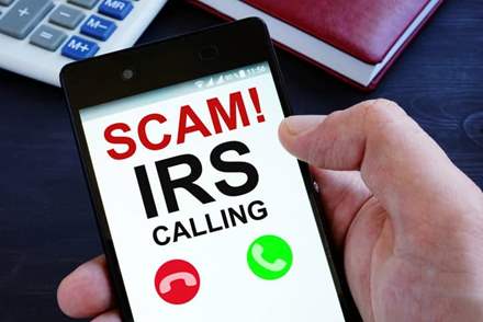 Person holding phone displaying an IRS scam call.