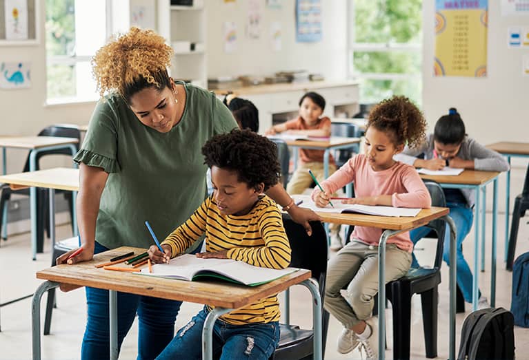 Teacher assisting student with work at their desk