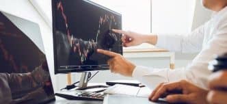 Portfolio managers discussing analysis with profit from the screen stock on the computer in the office.