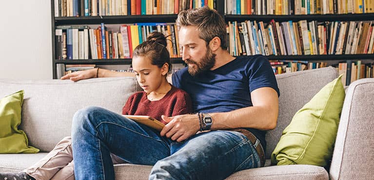 father on couch with daughter on tablet