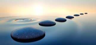 Stones in calm water with evening sun with horizon. Tranquil scenery.
