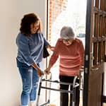 Young woman assisting her mother getting into the house