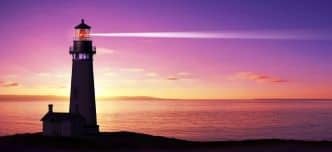 Lighthouse searchlight beam through marine air at night photo.