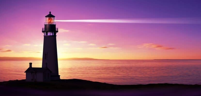 Lighthouse searchlight beam through marine air at night photo.