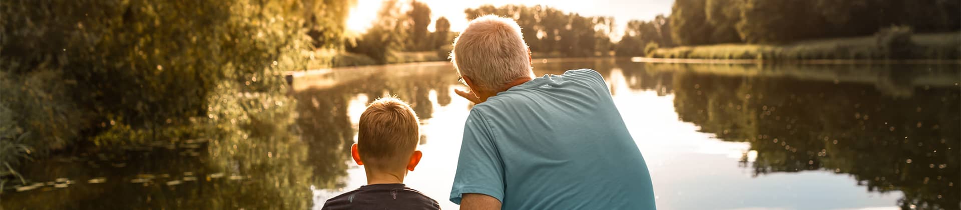 Grandfather and grandson watching the sunset at a lake