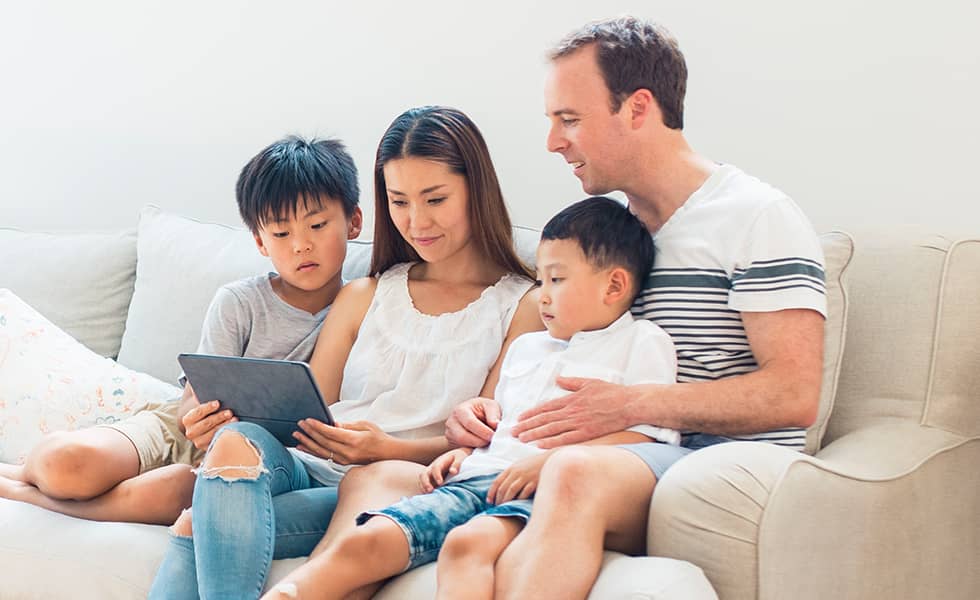 Family sitting together on couch with tablet