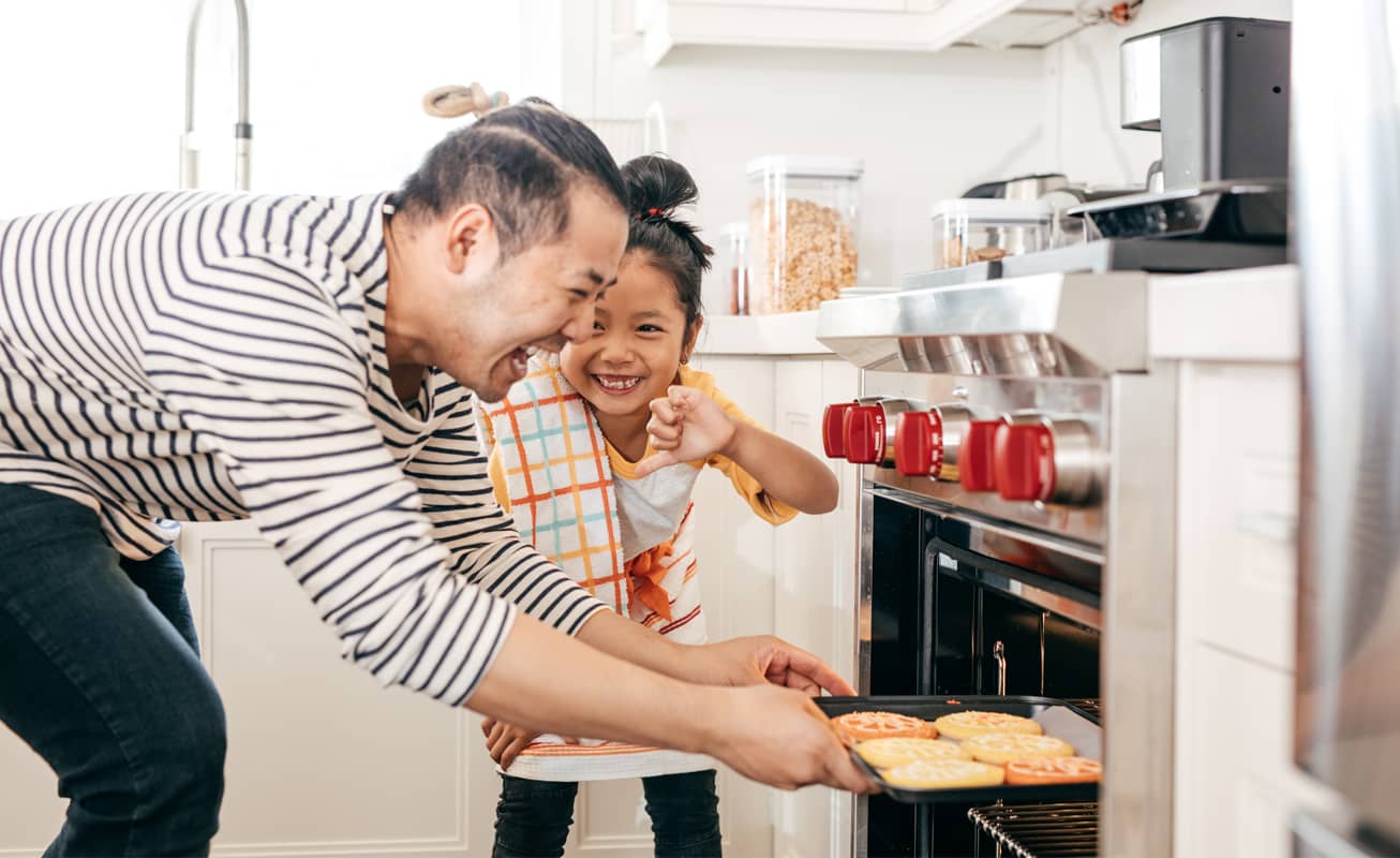 Father enjoying baking with daughter knowing their finances are protected 