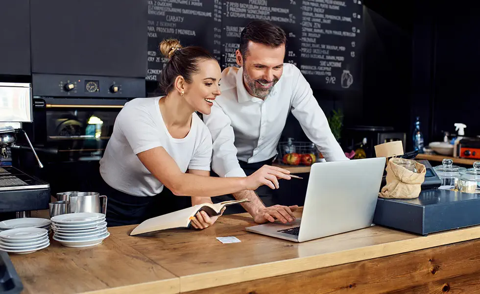Business partners reviewing computer together at coffee shop