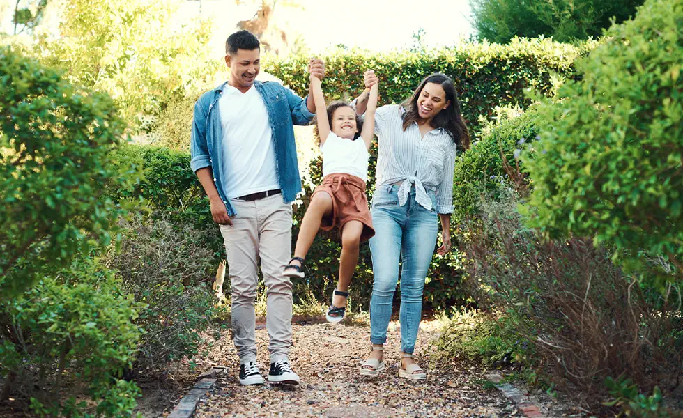 Family swinging their young daughter outside