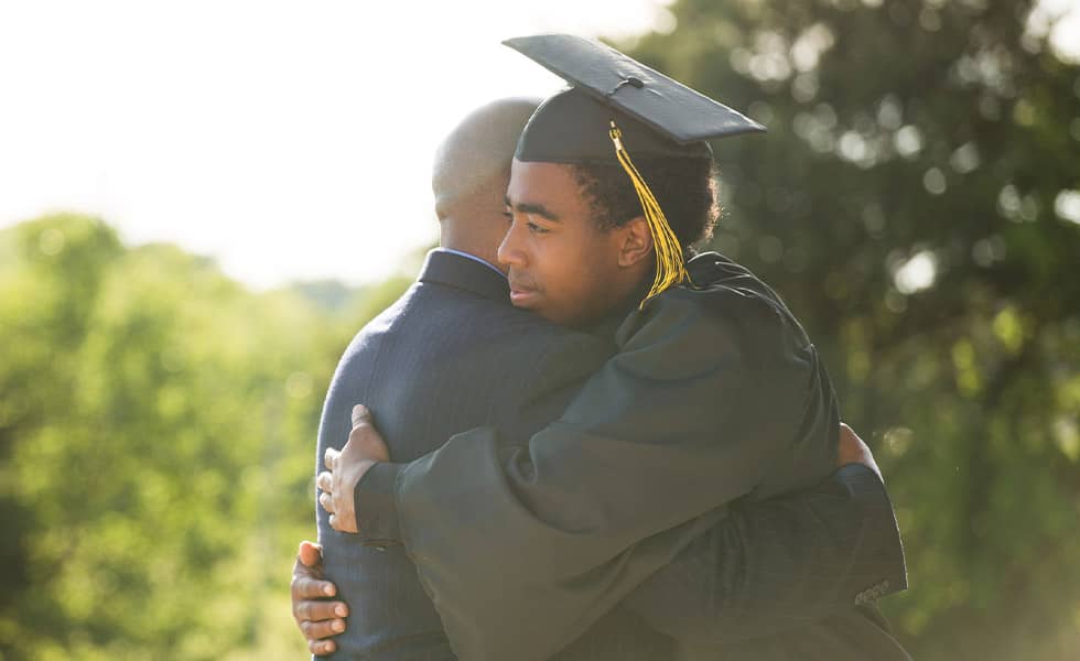 Young graduate hugging his father