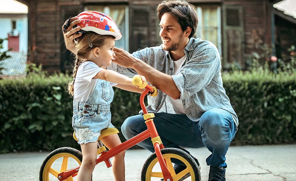 Father putting helmet on daughter for bike riding