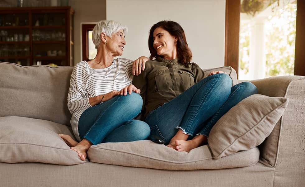 Young woman talking with her mother while lounging on the couch together