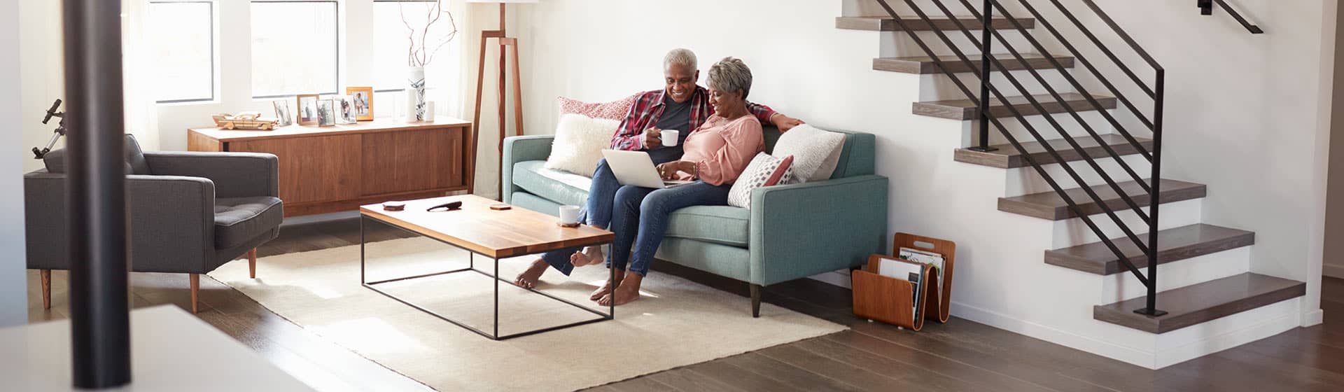Elderly Couple on the couch using their laptop to check retirement savings numbers