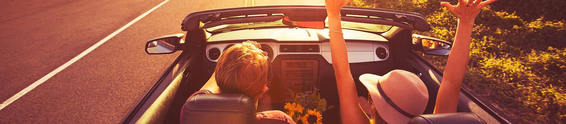 Couple driving convertible at sunset