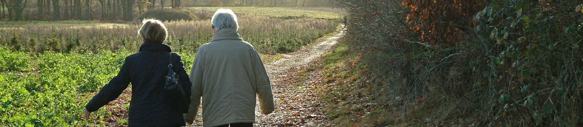 Two retired women walking on a path in the autumn