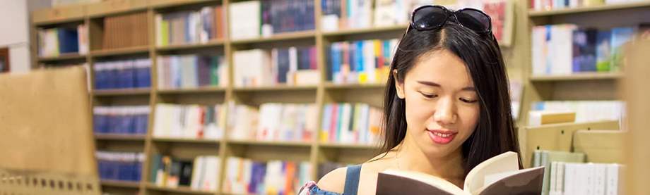 female college student looks through text in bookstore and reflects on financial planning for expenses