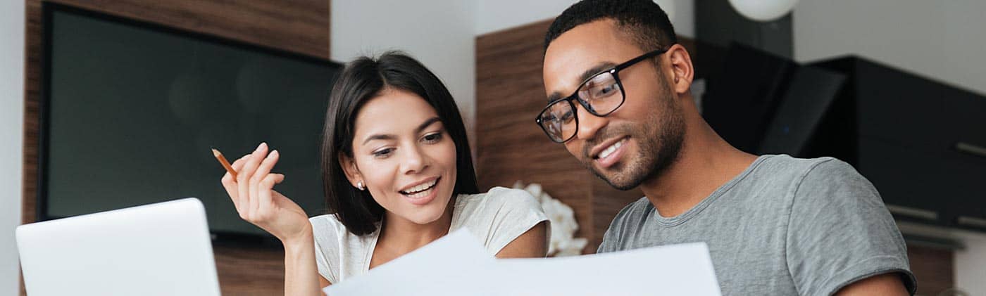 young couple reviews financial documents at home and enjoys the benefits of compounding interest