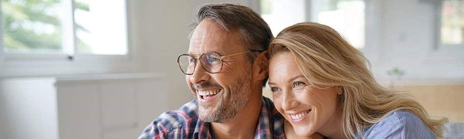 happy 50-something couple relaxes at home and asks each other: how much do I need to retire at 55?