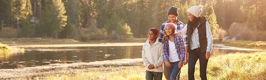 A family of four discusses the advantages of life insurance while on a sunny hike 