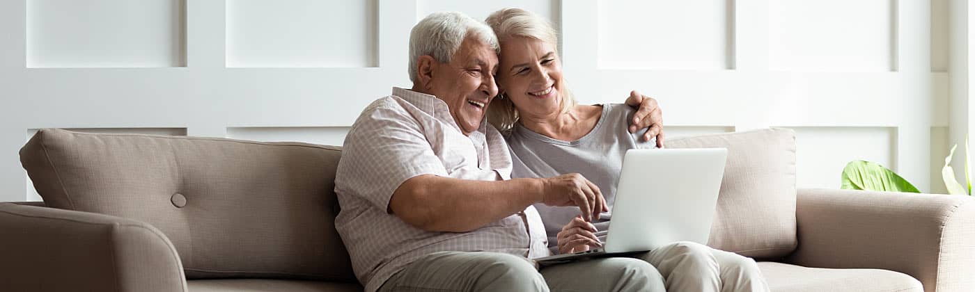 A mature couple sits together on a couch and reviews their overfunded life insurance policy 