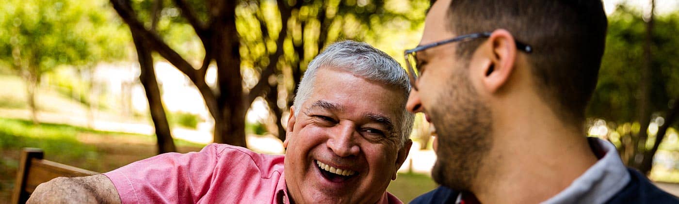 a mature father and his middle aged son laugh together in a park fixed indexed annuity
