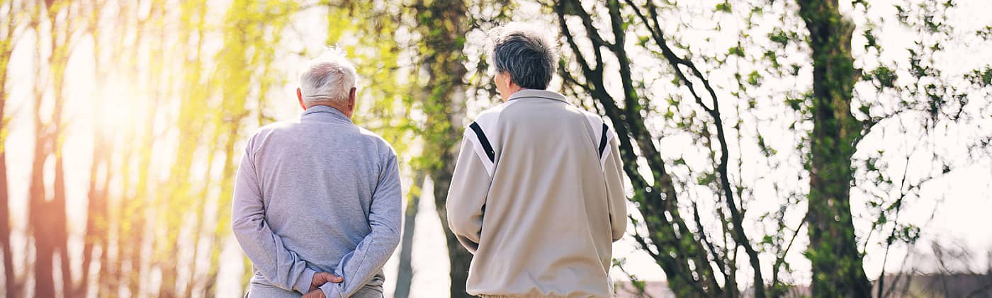 elderly father walks with his adult son down a path at sunset as they discuss estate executor duties