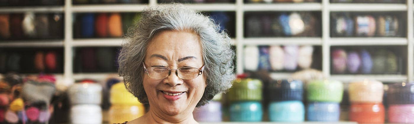 mature woman crochets in her home studio as she considers moving her previous 401(k) into a rollover IRA