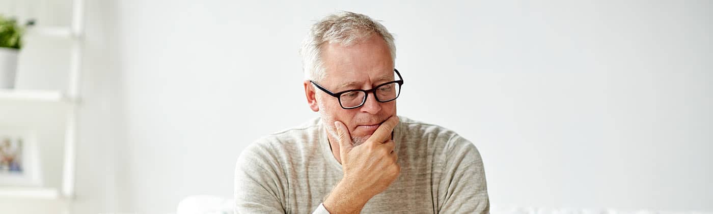 A pensive man wondering whether cashing out your 401(k) to pay off debt is the right move 
