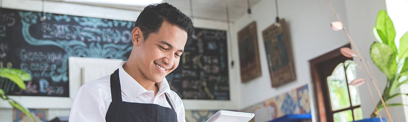 A small business owner in the doorway of his store considering small business tax deductions 