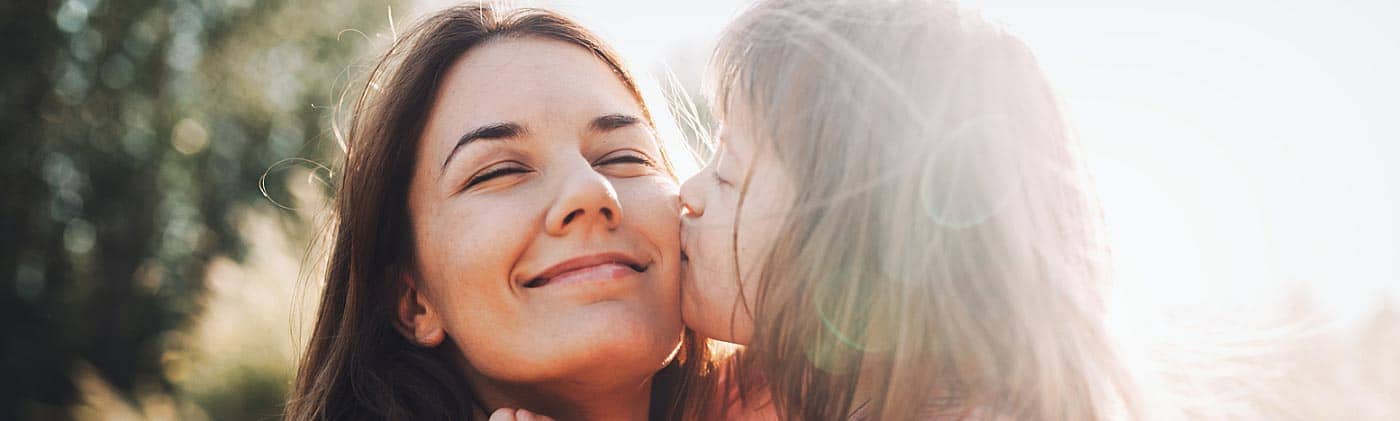young girl outside kisses her mother, who cares for her daughter with special needs planning