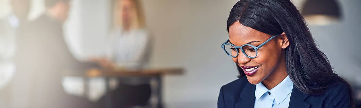 A young, smiling professional opening an investment account on her laptop 