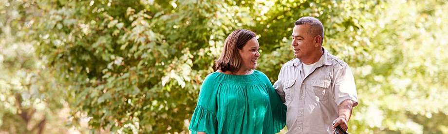 A couple takes their dog for a walk in their neighborhood and discusses how to invest for retirement