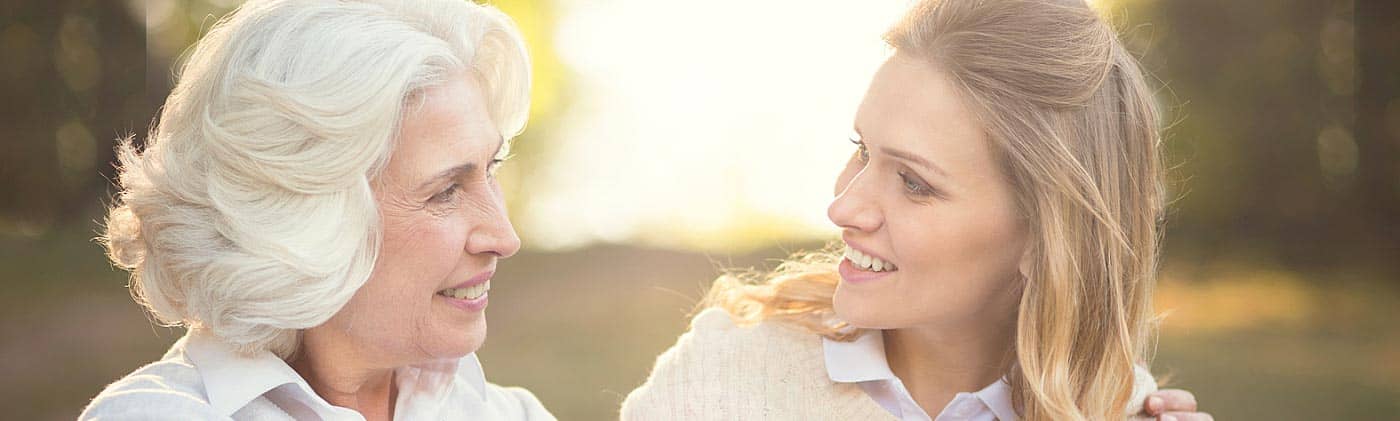 adult daughter talks with her aging mother outside on a sunny day about family financial planning