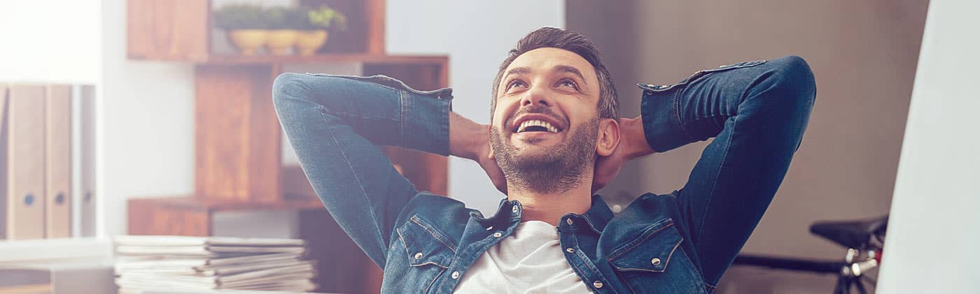 Adult man sitting behind laptop contemplating what's the difference between an ETF and a mutual fund 