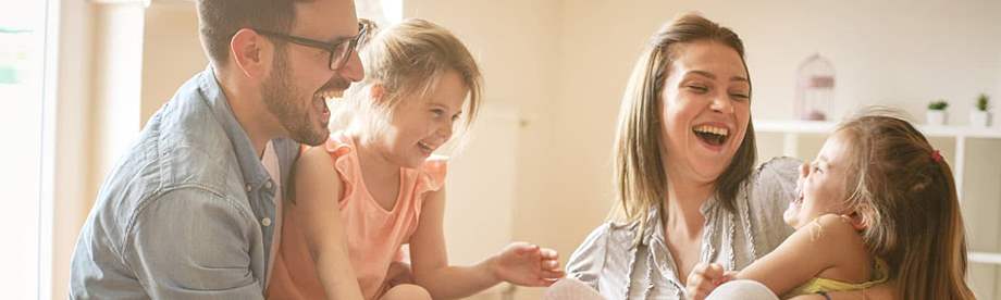 A mother and father play with their two young girls after choosing their life insurance beneficiary